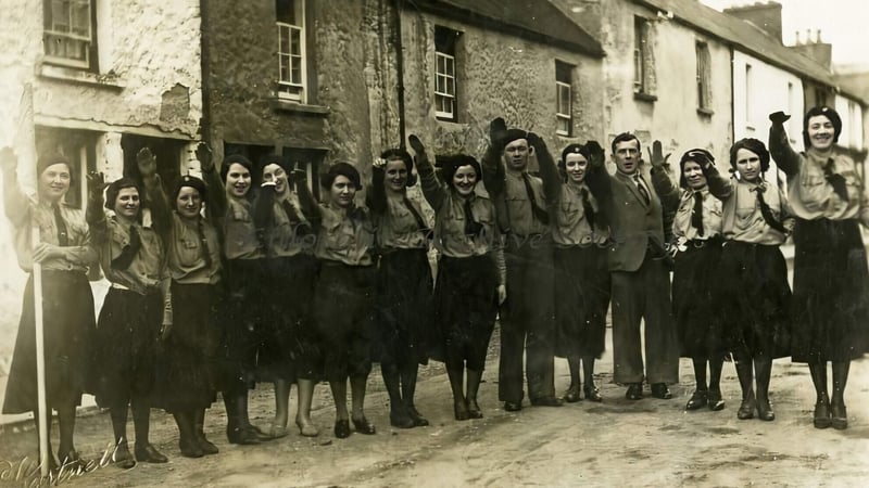 A line of mostly women (Blue Blouses) with some men (Blueshirts) all giving a stiff-armed fascist salute. RTE. Click to enlarge.